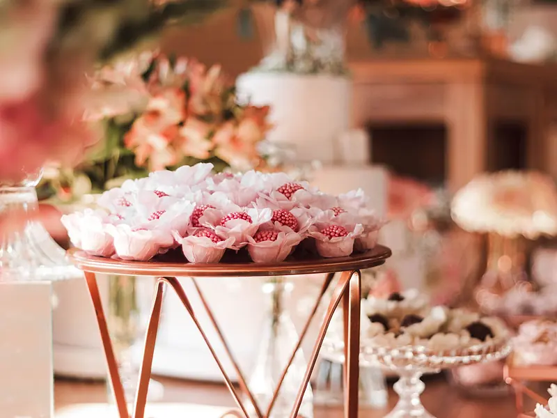 Mesa de dulces de boda con postres individuales en tonos rosa sobre base de cobre