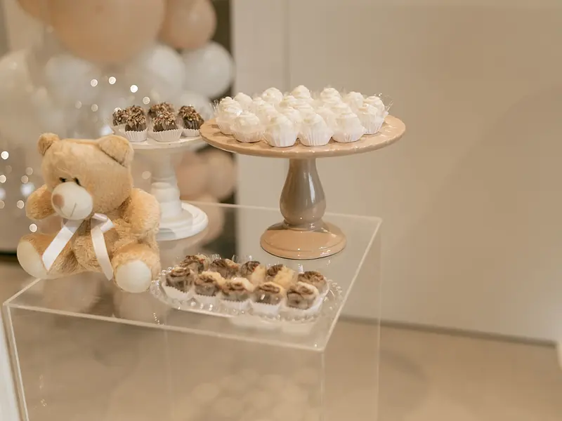 Mesa de dulces de baby shower en tonos pastel con merengues, bocadillos y osito de peluche