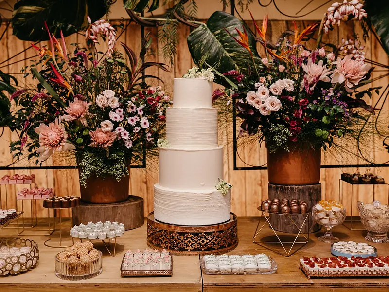 Mesa de dulces para boda con pastel de pisos, postres individuales y arreglos florales