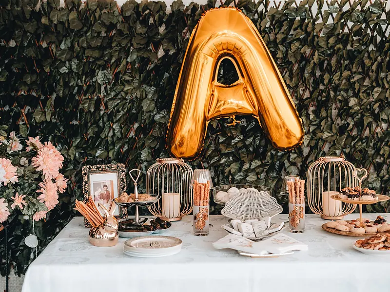Mesa de dulces para graduación con globo metálico dorado, postres y decoración floral